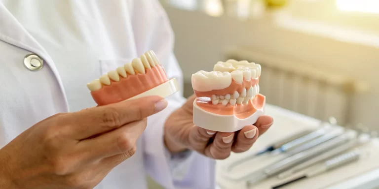 Dental models comparing the pros and cons of dentures vs implants.
